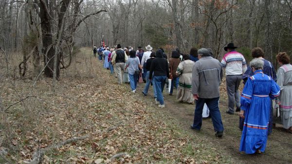 Men walking outdoors among nature's trees.