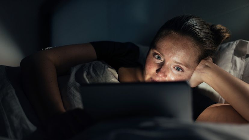 A woman watching a movie on her laptop at night. 