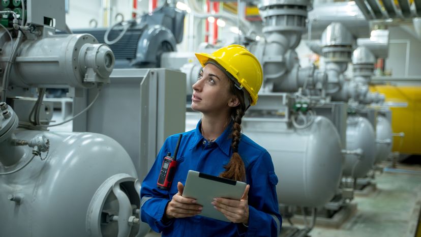 A female electrical engineer working in a control room at a thermal plant. 