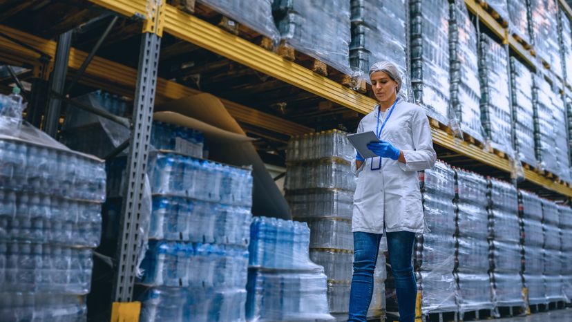 A woman making inventory of bottled water in a factory. 