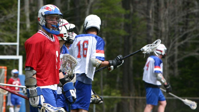 High school lacrosse player with his team mates on the field. 