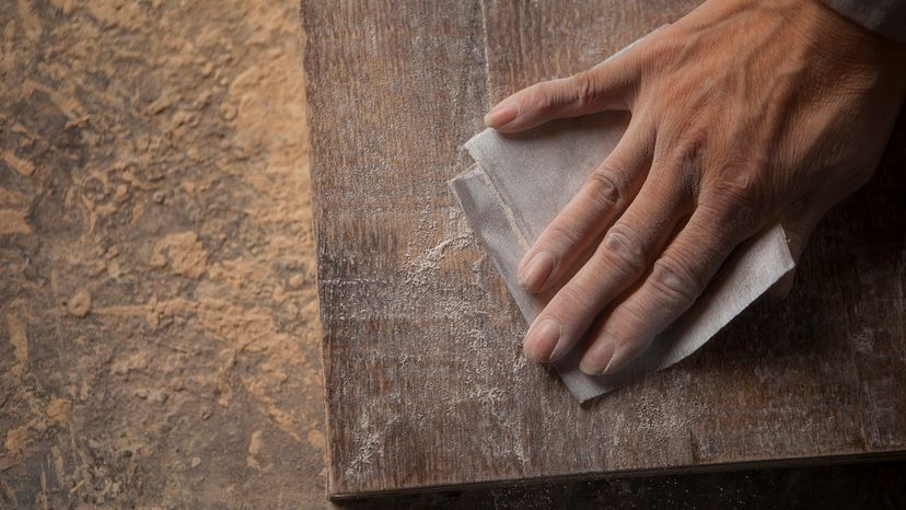 A man using a sandpaper on a wooden surface. 