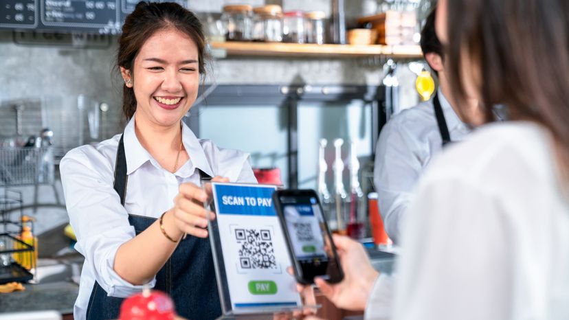 A business owner showing a customer the QR code for receiving payment. 
