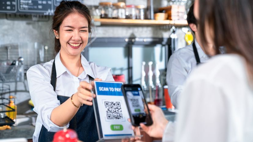 A business owner showing a customer the QR code for receiving payment.