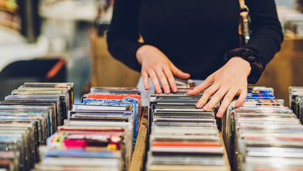 A woman going through a collection of DVDs at a store. 