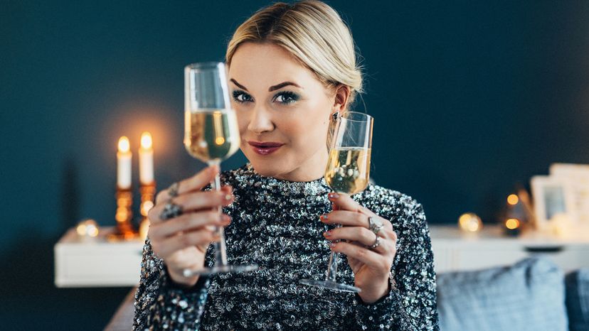 A woman wearing a sequin dress while drinking champagne. 
