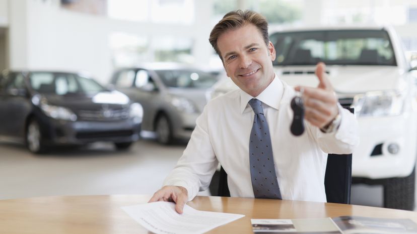 A car salesman holding up a car key. 