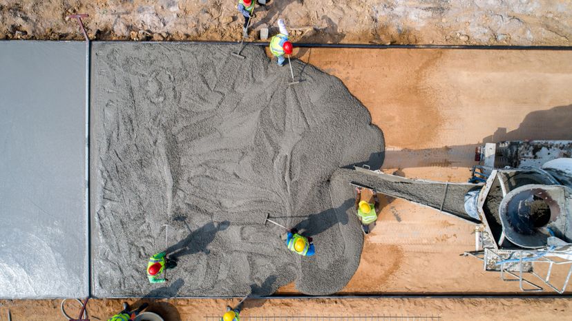 A construction worker pouring wet concrete at a construction site. 