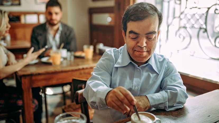 A dwarf businessman having a cup of coffee at a cafe. 