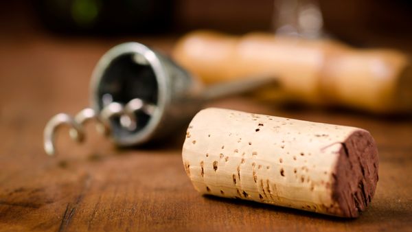 A wine cork with a cork screw in the background 