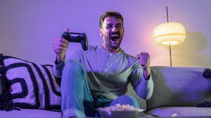 A young man holding a PlayStation pad while cheerfully shouting. 