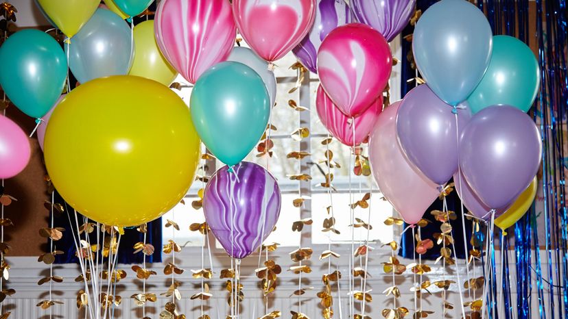 A group of different colored balloons during a birthday celebration. 