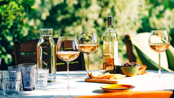 A wine glass, bottle and appetizer on a table. 