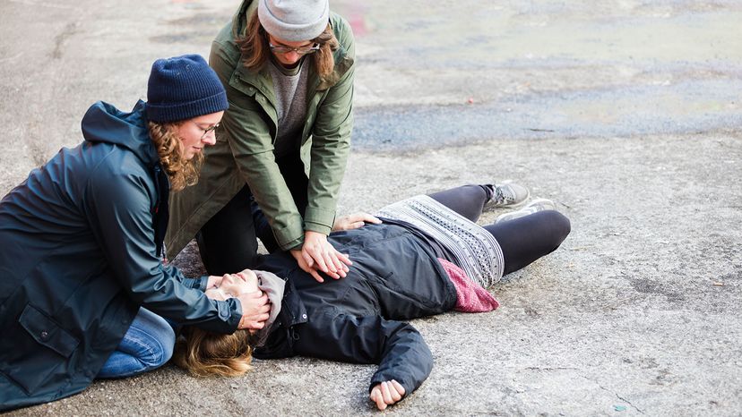 Two women perform CPR on another woman