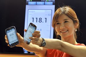 一名韩国模特通过SK电信(SK Telecom)在首尔的新移动网络，展示两款Galaxy S4智能手机的无线数据传输速度。查看更多电信图片。查看更多手机图片。＂width=