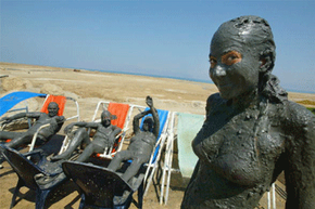 A tourist at the Dead Sea covers herself in rejuvenating mud before taking a dip in the famous waters.