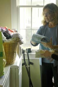 woman with arm crutches folding laundry