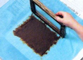 When most of the water has been pressed out, lift the frame away from the pulp. It should stick to the sheet without any holes.