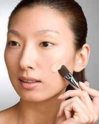 Woman applying concealer to face. 