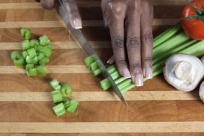 woman chopping celery on wooden cutting board