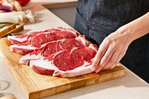 woman cutting steaks on cutting board