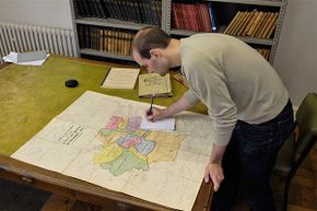 A man researches family history with a map in Bath Records Office, England.