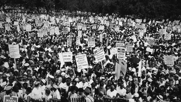 Protesting crowd holds black and white signs for political change.