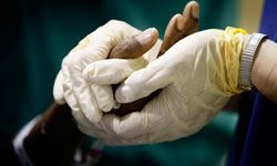 A doctor holds a patient's hand during surgery at the University of Miami Miller school of Medicine hospital-Haiti as they help the people injured during the massive earthquake on January 26, 2010 in Port-au-Prince, Haiti.