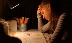 A student hunched over her books and notes at night.