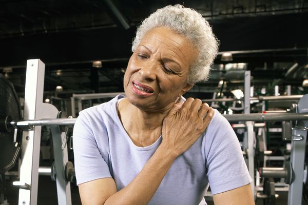 A senior woman in gym rubbing her aching shoulder.