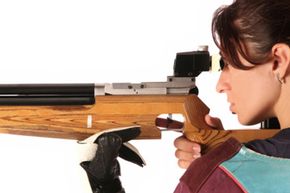 Woman peering down gun barrel