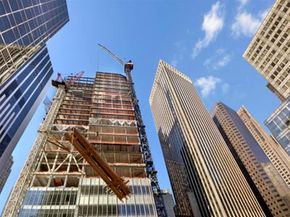 Skyscraper under construction with steel beam on crane, low angle view