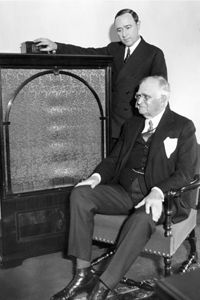 Merlin H. Aylesworth (standing), President of NBC, and Paul D. Cravath (sitting), President of the Metropolitan Opera Company, listening to the opera on the radio after making their introductory remarks on Christmas Day in 1931.