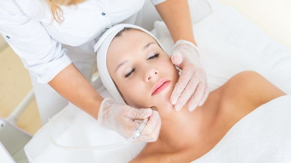 Young woman receiving facial microdermabrasion treatment
