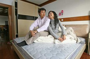 Lu Qin (left) and Li Chunqing pose on their bed in the new flat that they bought before their marriage in 2007 in Shanghai, China.