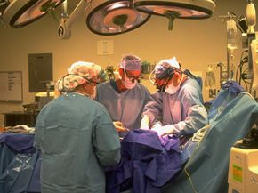A pair of University of Virginia Medical Center surgeons perform a coronary bypass operation, as a third colleague looks on.