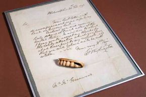 A replica of one of George Washington's dentures is shown along with a copy of his letter written to his dentist Mr. Greenwood thanking him for his attentiveness. Greenwood made this denture from a gold plate with ivory teeth riveted to it.