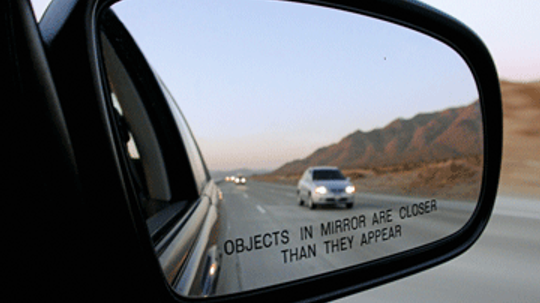 Why are objects in the side-view mirror closer than they appear?