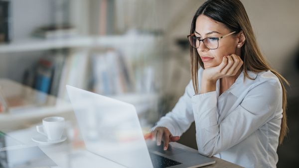 A woman wearing a glass, working on laptop.