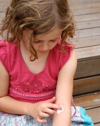 little girl putting on lotion