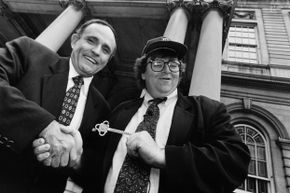 1994, Mayor Rudy Giuliani and filmmaker Michael Moore stand in front of a building shaking hands and clasping a ceremonial key.