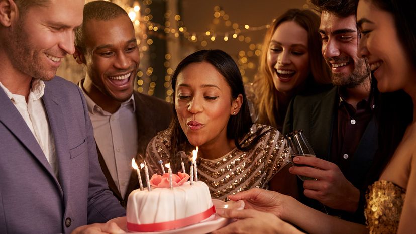 Woman Blowing Out Candles On Birthday Cake