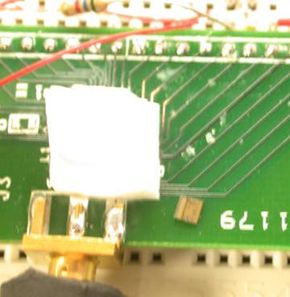 &quot;Spec,&quot; a single-chip mote (hiding under the white wax square), measures approximately 2mm x 2.5mm, has an AVR-like RISC core, 3K of memory, an 8-bit, on-chip ADC, an FSK radio transmitter, a Paged memory system, communication protocol accelerators, register windows, and much, much more.