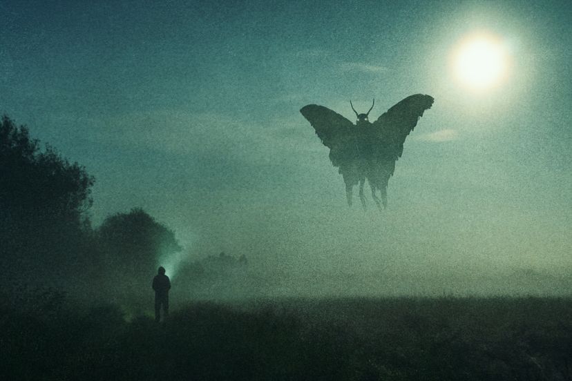 A figure with a flashlight looks at a giant moth-like creature silhouetted against the full moon