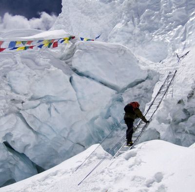 Man climbing on mountain with help of ladder on Mount Everest, Tibet