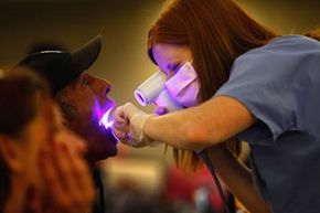 Dental hygiene student Audrey Rayniak gives an oral cancer screening to Kevin Smith at a free dental clinic in Brighton, Colo.