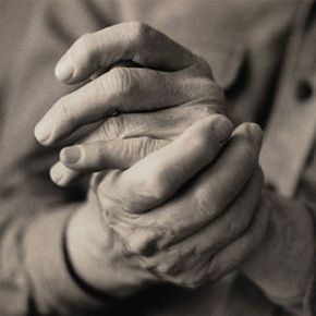 Mature adult rubbing hands, close-up (grainy B&W)