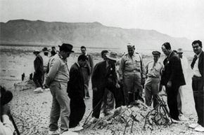 Officials from the Manhattan Project, the code name for the U.S. plan to develop atomic weapons, inspect the detonation site of the Trinity atomic bomb test. That's Dr. Robert J. Oppenheimer in the white hat.