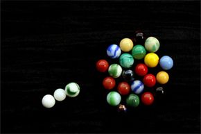 If you think of critical mass in terms of marbles, the tight formation of marbles represents critical mass and the three lone marbles stand in for neutrons.