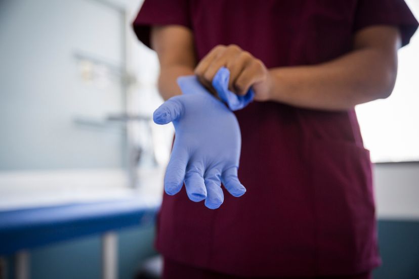 Midsection of female nurse wearing protective gloves in hospital